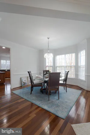 a kitchen with stainless steel appliances granite countertop a stove top oven a dining table and chairs with wooden floor