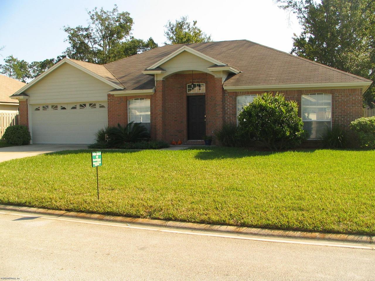 a view of a house with a yard and large tree