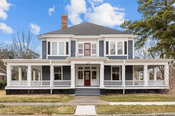 a large white building with a large windows and small yard in front of it