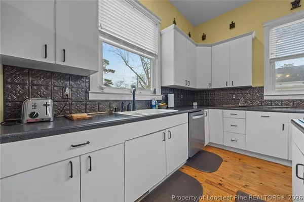 a kitchen with white cabinets and window