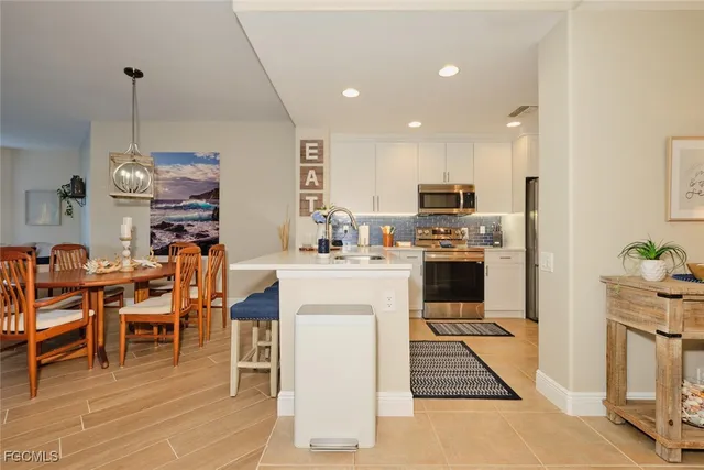 a kitchen with stainless steel appliances granite countertop a stove top oven a sink a dining table and chairs with wooden floor