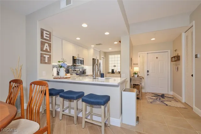 a kitchen with a dining table chairs and white cabinets