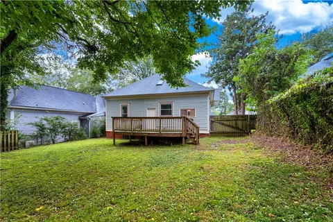 a view of deck and yard with trees in the background