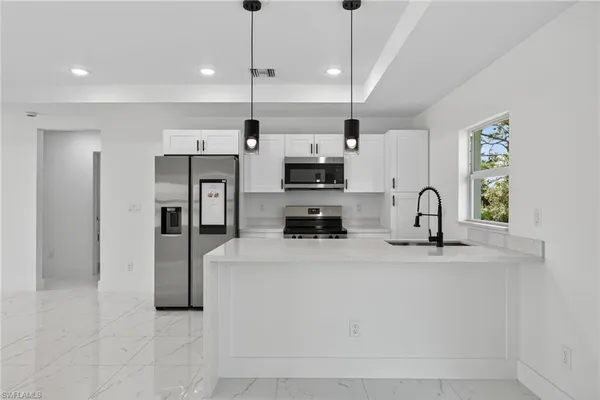 a kitchen with stainless steel appliances granite countertop a sink a stove and a refrigerator