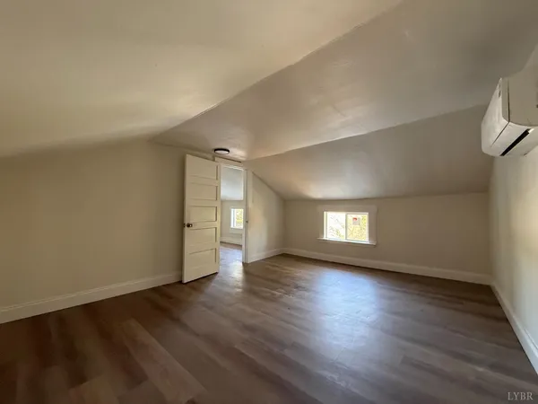 a view of an empty room with wooden floor and window