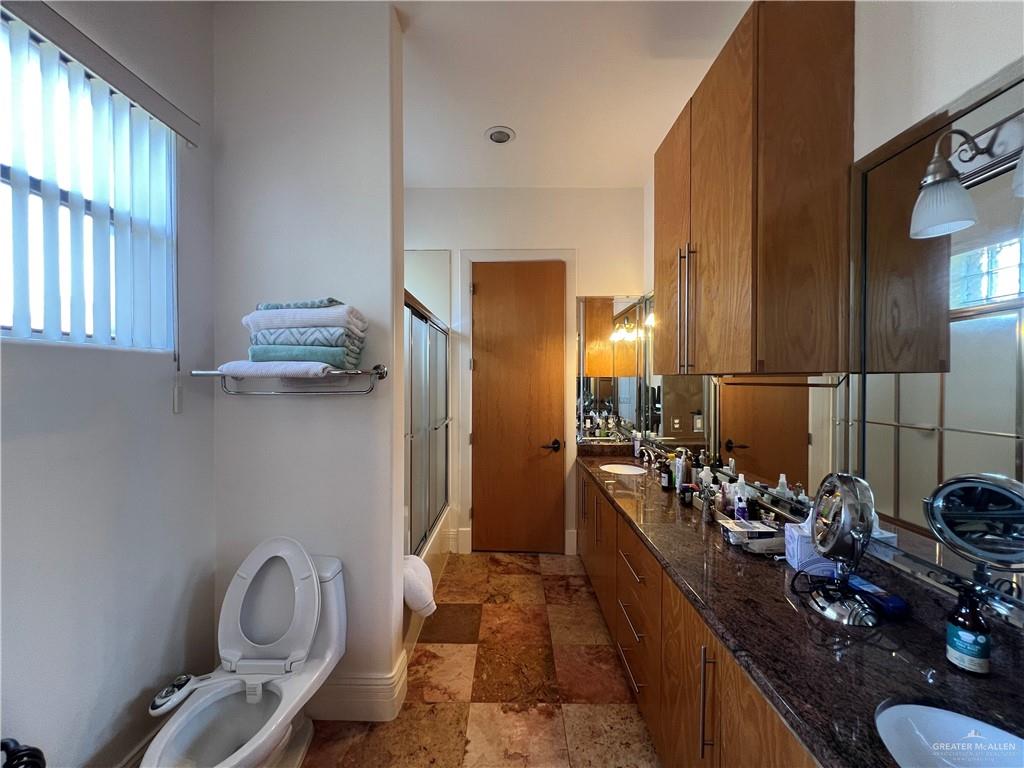 416 Frio Street Mission, TX 78572 - Photo 14 of 35 a bathroom with a granite countertop sink a toilet and mirror