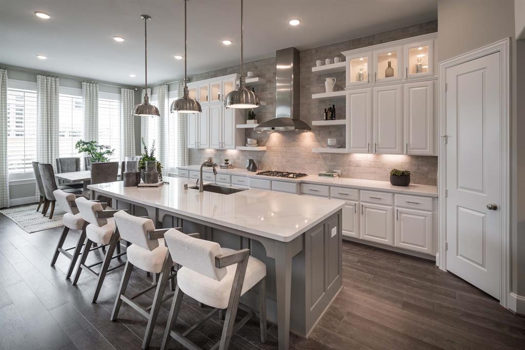 a kitchen with kitchen island granite countertop a sink and white cabinets with wooden chairs
