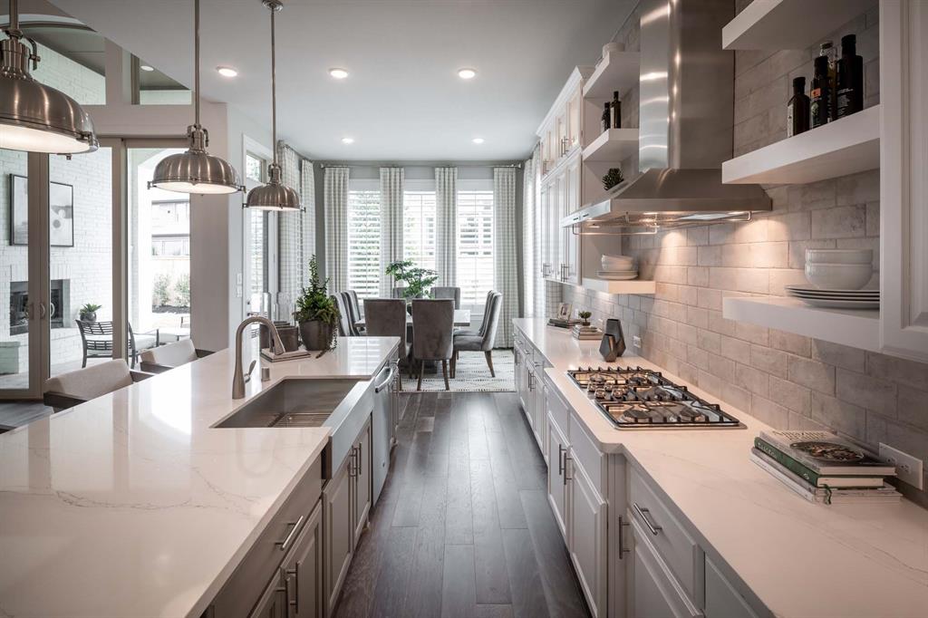 931 Fallkirk Drive Prosper, TX 75078 - Photo 3 of 7 a kitchen with stainless steel appliances kitchen island granite countertop a stove a sink a refrigerator and couches with wooden floor