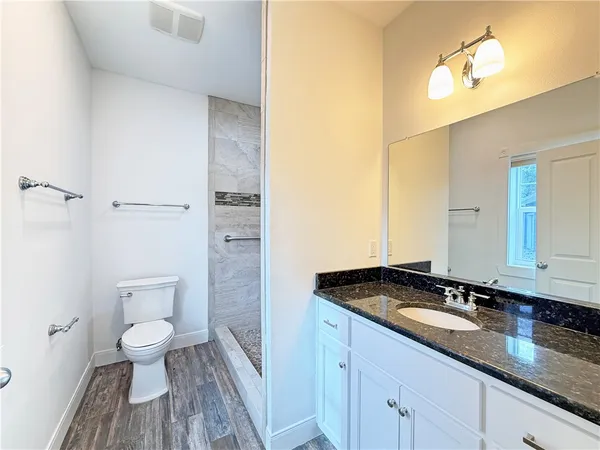 a bathroom with a granite countertop sink a toilet and a mirror