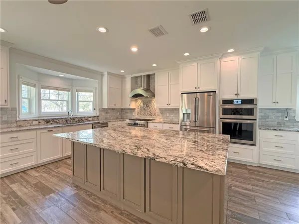 a kitchen with kitchen island granite countertop a sink stove and refrigerator