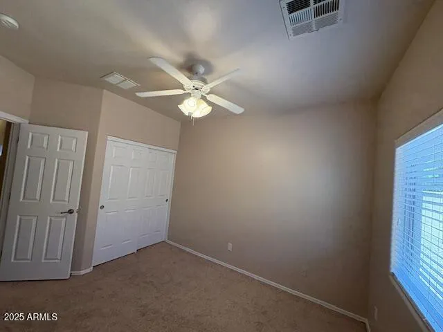 an empty room with windows and fan