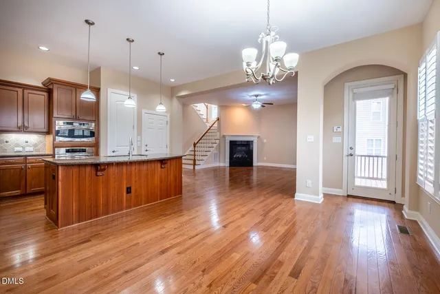 a view of a kitchen with granite countertop wooden floor stainless steel appliances and a chandelier