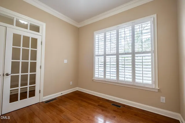a view of an empty room with a window and wooden floor