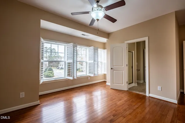 a view of an empty room with a window and wooden floor