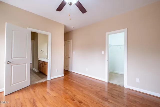 an empty room with wooden floor and ceiling fan