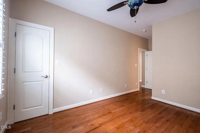 an empty room with wooden floor fan and windows