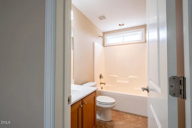 a bathroom with a granite countertop bathtub shower sink vanity and toilet