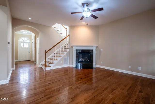 a view of an empty room with wooden floor and a ceiling fan