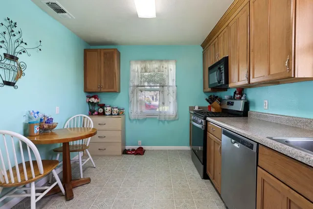 a kitchen with stainless steel appliances a stove a sink cabinets and a dining table