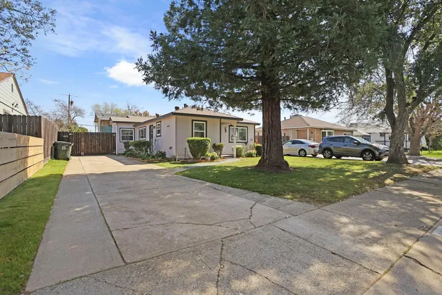 a front view of a house with garden and trees
