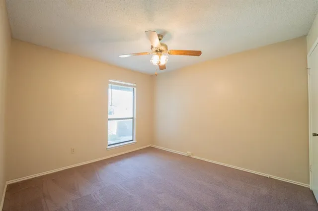 an empty room with a window and a ceiling fan