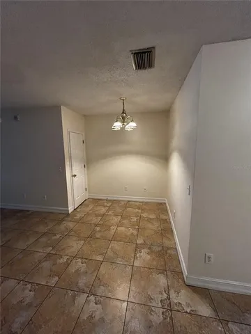 a view of a refrigerator in kitchen and an empty room