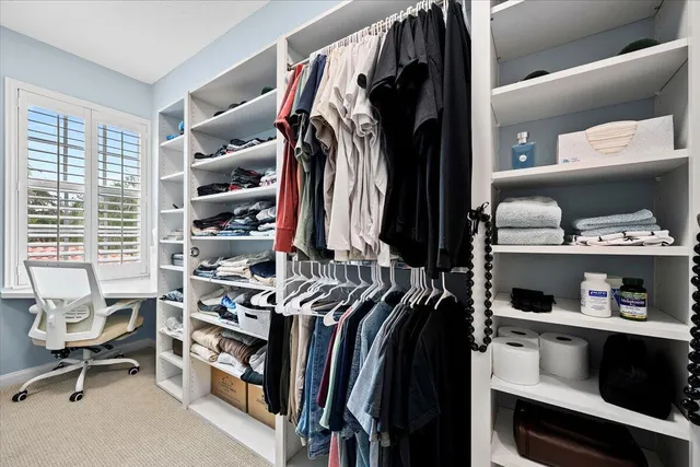 a view of walk in closet with clothes and shoes