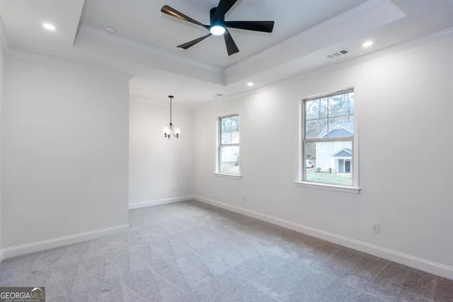 an empty room with mirror and a ceiling fan