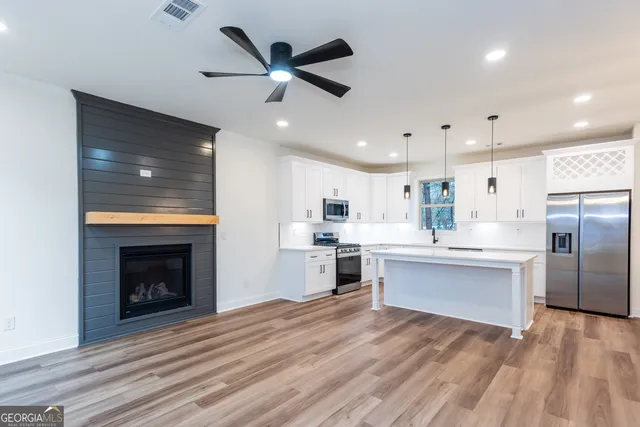a large white kitchen with wooden floors and view living room