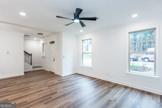 an empty room with windows a fireplace a ceiling fan and wooden floor
