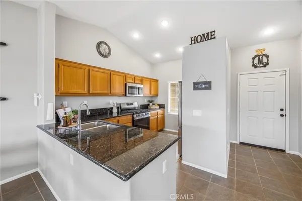 a kitchen with stainless steel appliances granite countertop a stove a sink and a microwave