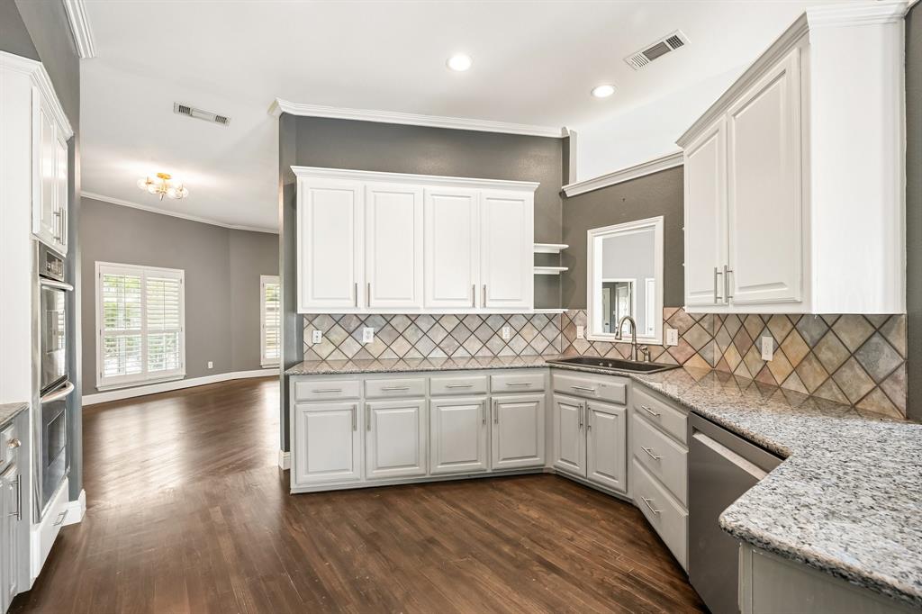 1380 Meandro Ria Lane Fairview, TX 75069 - Photo 12 of 39 Elegant kitchen showcasing white cabinetry, stainless steel appliances, and a geometric tile backsplash