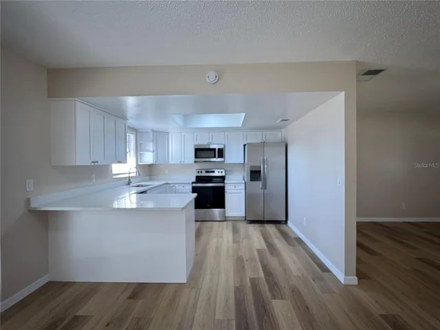 a kitchen with kitchen island white cabinets stainless steel appliances and sink