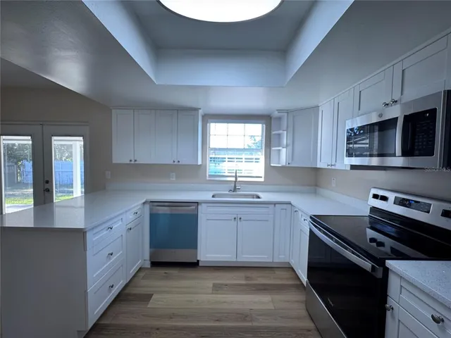 a large kitchen with stainless steel appliances granite countertop a sink dishwasher a stove and a microwave oven with cabinets