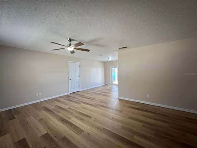 a view of a room with wooden floor and a ceiling fan
