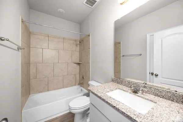 a bathroom with a granite countertop sink toilet mirror and bathtub
