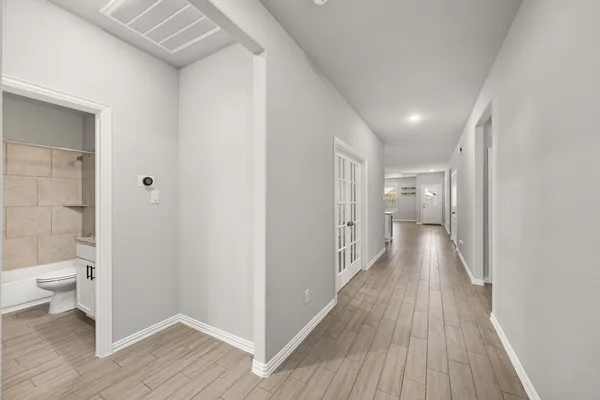 a view of a hallway with wooden floor and a bathroom