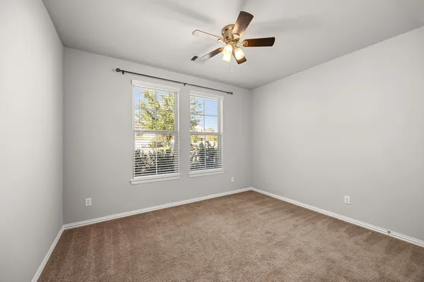 an empty room with a window and a ceiling fan