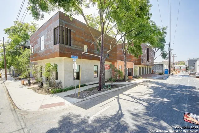 a view of a white house with large tree and plants