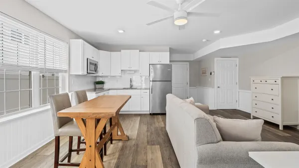 a kitchen with stainless steel appliances kitchen island granite countertop a dining table chairs and a refrigerator