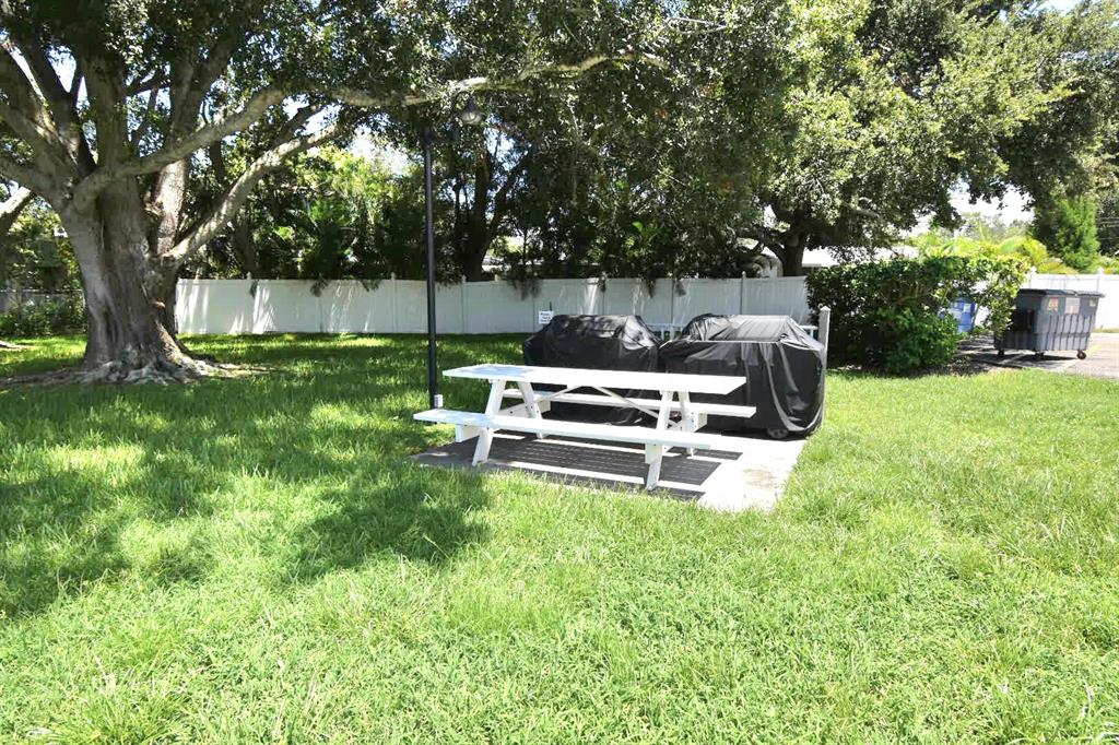 946 Virginia Street, Unit 102 Dunedin, FL 34698 - Photo 25 of 30 a white bench sitting in the middle of a yard