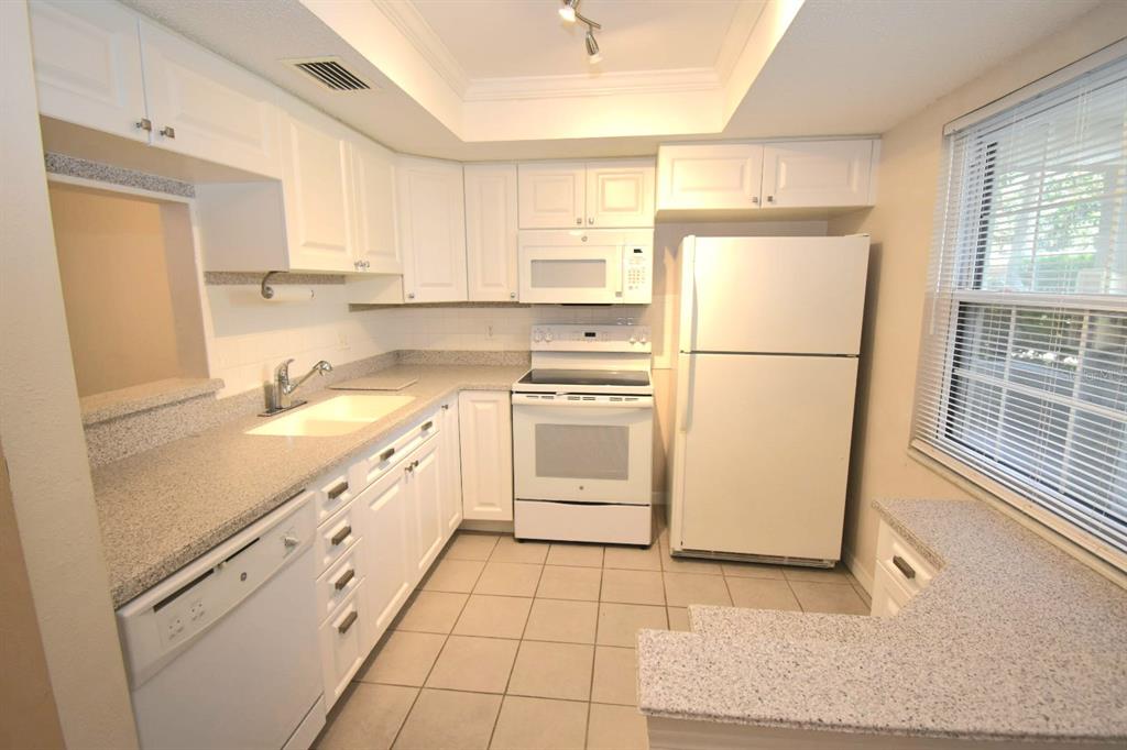 946 Virginia Street, Unit 102 Dunedin, FL 34698 - Photo 6 of 30 a kitchen with white cabinets and white appliances