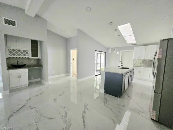 a kitchen with granite countertop a sink a stove top oven and cabinetry