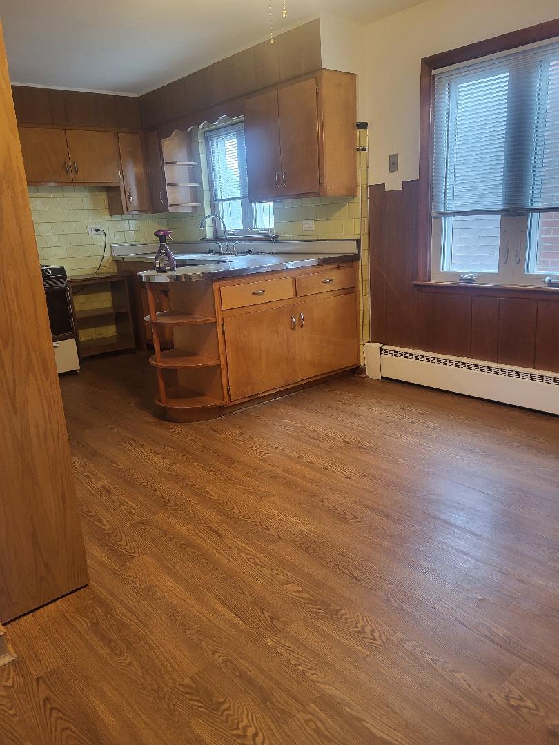 5549 South Meade Avenue, Unit 2 Chicago, IL 60638 - Photo 4 of 7 a view of a kitchen with kitchen island a sink wooden floor and a window