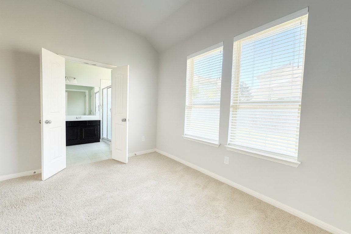 913 Centerra Hills Circle Round Rock, TX 78665 - Photo 5 of 10 Unfurnished bedroom with light colored carpet, vaulted ceiling, and ensuite bath