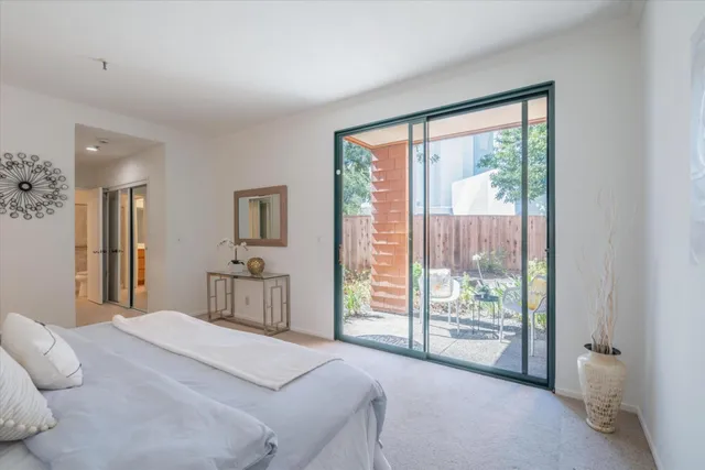 a bedroom with a white bed and a lamp on dresser
