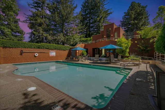 a view of swimming pool with a table and chairs under an umbrella