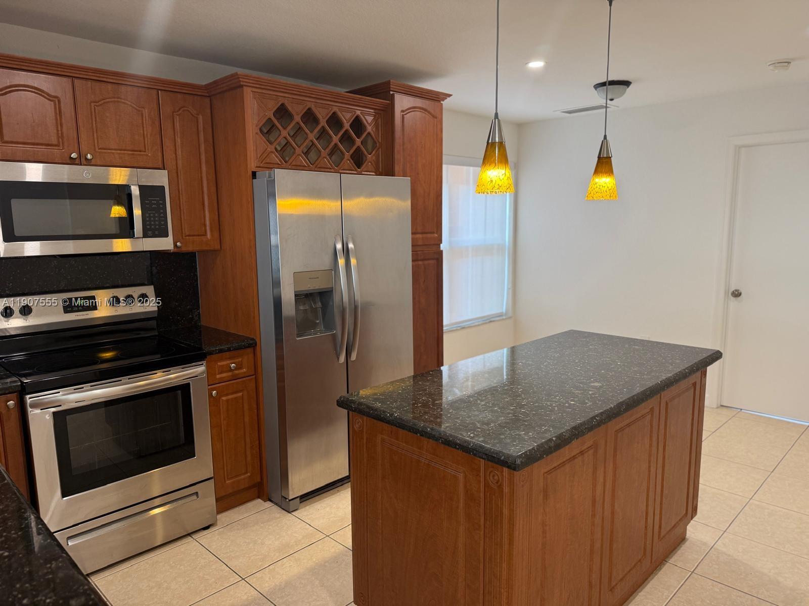 15530 Southwest 26th Terrace Miami, FL 33185 - Photo 5 of 26 a kitchen with stainless steel appliances granite countertop a stove a refrigerator and a microwave