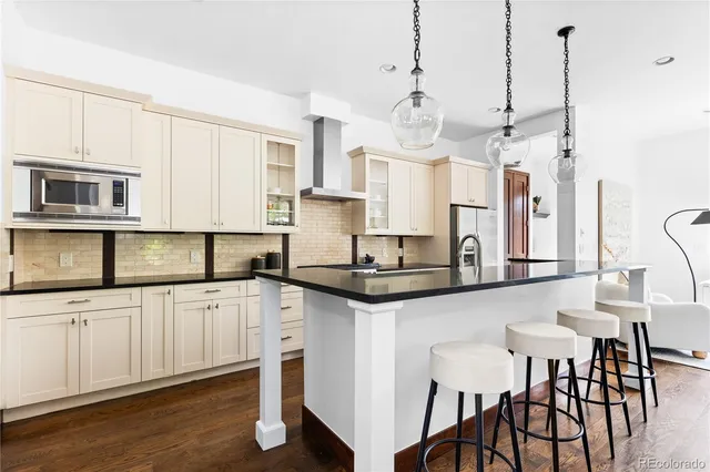 a kitchen with stainless steel appliances granite countertop a refrigerator a stove and white cabinets with wooden floor