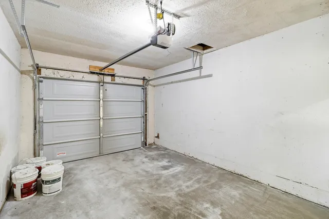 a view of a white house next to a yard with big trees